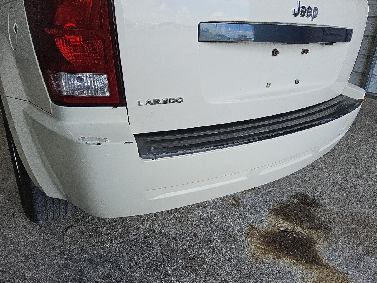 2009 Jeep Grand Cherokee Laredo White vin: 1J8GS48K59C538302 Damage: Rear Bumper, Peeling, 2 To 3 Inches